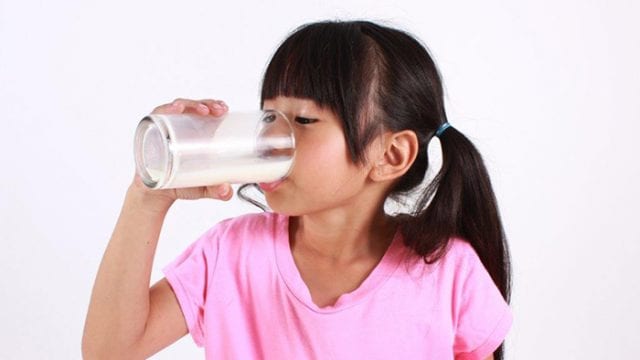 little girl drinking milk in a pink shirt