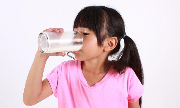 little girl drinking milk in a pink shirt
