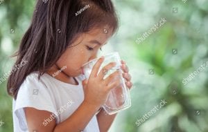 young girl drinking water out of a glass