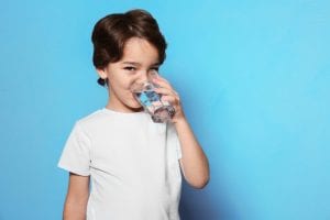boy on blue background drinking water