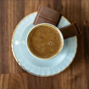Mug of coffee on plate with chocolate