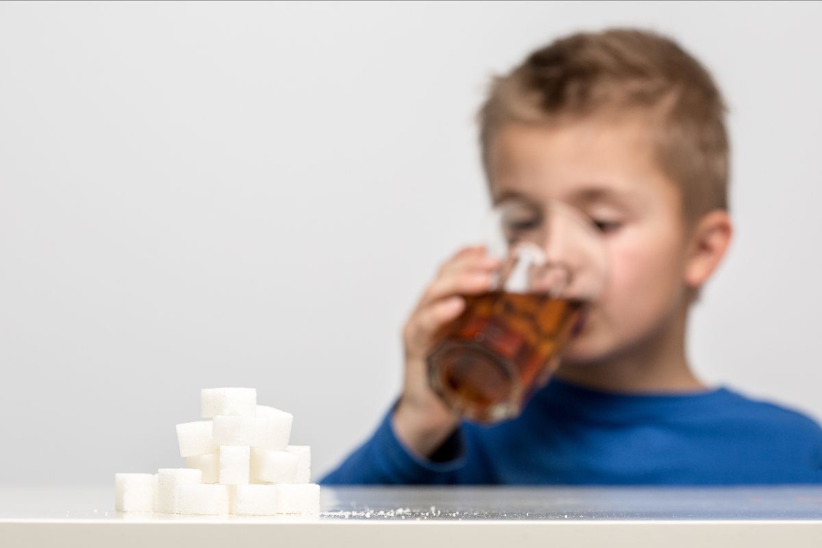 Child drinking soda behind stacked sugar cubes