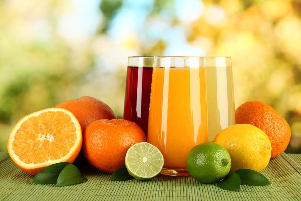 Fruit juice in clear glasses next to citrus