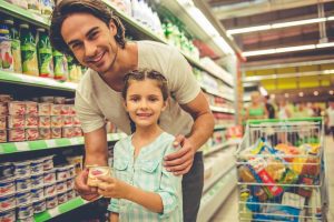 Daughter holding can in grocery store with father.