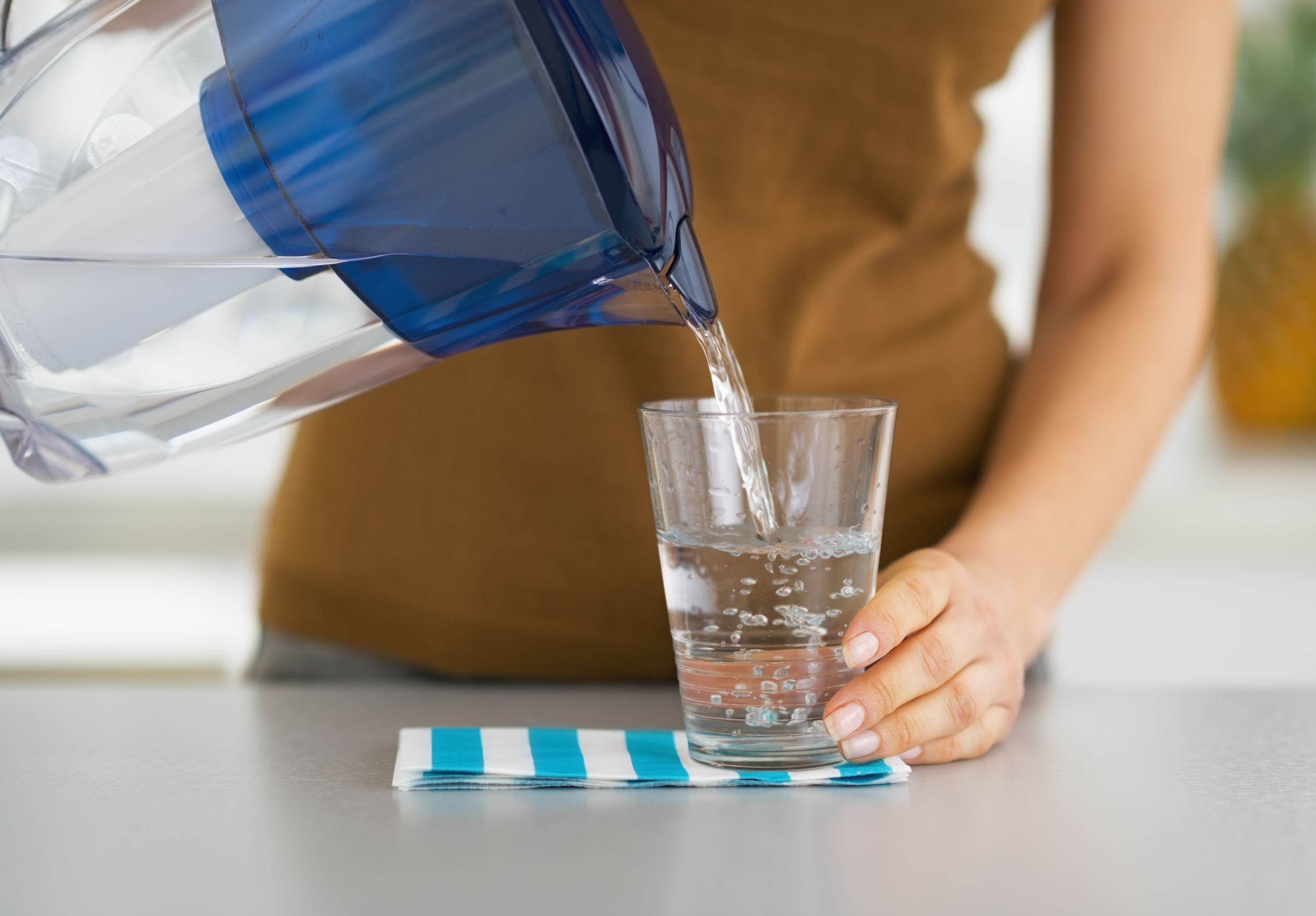 Woman pouring water into a glass from a water filter pitcher